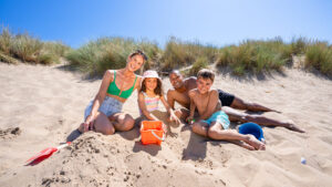 A family relaxing on the beach in front of sand dunes on a sunny day