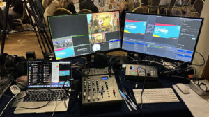 Monitors and computer equipment on a table with a video mixing desk